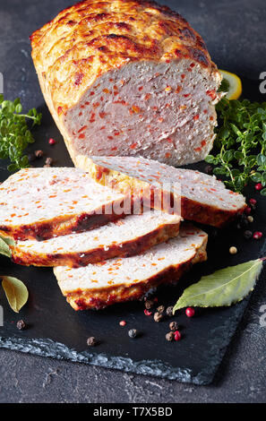 Close-up de tranches de pain de viande de poulet sur une plaque en ardoise noire avec les tranches de citron et thym frais sur une table en béton, vertical Vue de dessus Banque D'Images