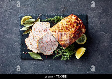 Close-up de tranches de pain de viande de poulet sur une plaque en ardoise noire avec les tranches de citron et thym frais sur une table, une vue de dessus, flatlay Banque D'Images