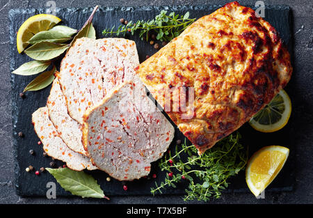 Close-up de tranches de pain de viande de poulet sur une plaque en ardoise noire avec les tranches de citron et thym frais sur une table, une vue de dessus, flatlay Banque D'Images