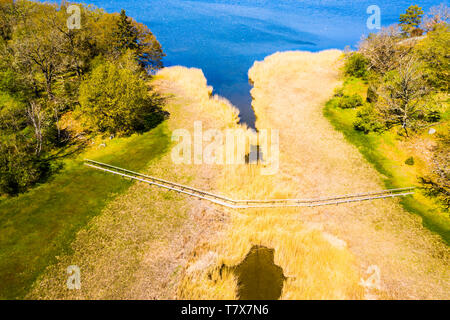 Passerelle en bois sur un sentier de randonnée donne un passage sûr à travers un étroit détroit. Un beau jour de printemps dans l'archipel suédois de Blekinge Banque D'Images