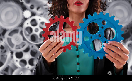Businesswoman essaie de se connecter gears pièces. Concept d'équipe, le partenariat et l'intégration. Banque D'Images