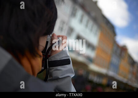 Tourné à l'épaule d'un touriste asiatique de prendre une photo au quartier de Nyhavn à Copenhague Banque D'Images