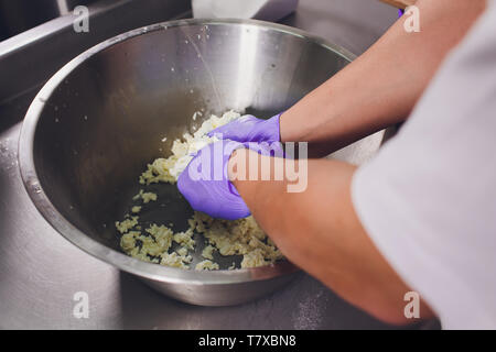 La fabrication du fromage traditionnel dans une petite entreprise. Bouilloire fromage mains Close-up Vue de dessus Banque D'Images