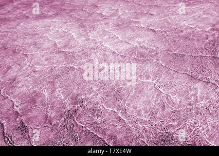 Résumé fond vide naturellement créés par de petites vagues en eaux peu profondes et de la lumière du soleil les réflexions sur la surface de l'eau. En mélange de tons lilas, p Banque D'Images