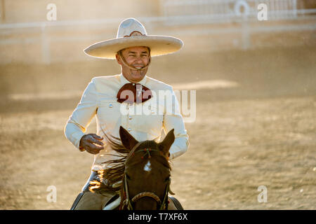 Juan Franco sourire après avoir réussi à Downing un bouvillon rides au cours de la Colas en el Lienzo de cause à la famille dans la session pratique Charreria Jalisco Highlands ville de Capilla de Guadalupe, au Mexique. Colas en el Lienzo ou Steer Tailing est similaire à bull dogging sauf que la personne ne réussit pas descendre ; le charro rides avec le côté gauche de la bulle, s'enroule sa queue autour de sa jambe droite, et tente d'amener le taureau par un rouleau comme il monte après lui. Banque D'Images