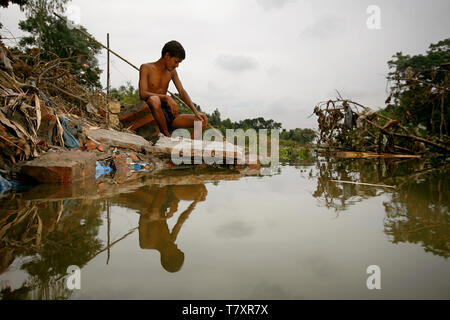 Mohammad Khokon à côté de ce qui était autrefois la maison de sa famille. Une crue éclair l'a emporté dans la rivière Jamuna à Sirajganj, au Bangladesh, en 2007. Le réchauffement climatique provoque la pluie de mousson et les inondations à commencer plus tôt. Le réchauffement climatique accentue également la fonte de la glace et de la neige dans l’Himalaya, qui alimente les rivières déjà saturées qui composent le delta du Gange. Le résultat est dévastateur pour les personnes qui vivent dans la région densément peuplée du delta. Alors que l'Himalaya et les inondations font des ravages depuis le nord, l'élévation du niveau de la mer provoque une intrusion d'eau salée dans les zones agricoles basses le long de th Banque D'Images