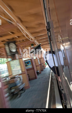 Train à vapeur britannique vintage arrivant à la plateforme de la gare du patrimoine de Bewdley. Garde rapprochée (inspecteur de billet) donnant sur la fenêtre du train. Flou de mouvement. Banque D'Images