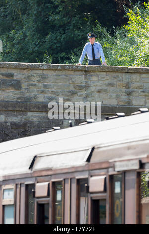 Severn Valley Railway, reconstituant la Grande-Bretagne pendant la guerre dans les années 40. L'homme en uniforme militaire se tient sur le pont de chemin de fer en regardant vintage train à vapeur. Banque D'Images