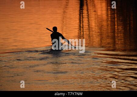 Silhouette d'un canoteur pagayant dans le coucher du soleil la réflexion sur l'Avon Banque D'Images