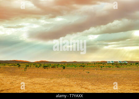 Lake au Maroc à l'aube au pied du désert du Sahara. Les rayons de soleil brillent à travers les nuages. Dans le cadre de la voiture et un groupe de touristes qui Banque D'Images