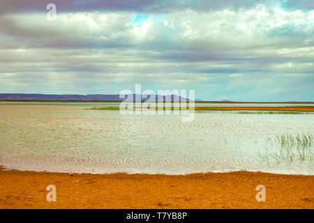 Lake au Maroc à l'aube au pied du désert du Sahara. Les rayons de soleil brillent à travers les nuages. Banque D'Images