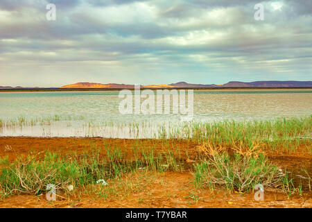 Lake au Maroc à l'aube au pied du désert du Sahara. Les rayons de soleil brillent à travers les nuages. Banque D'Images