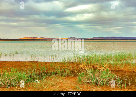 Lake au Maroc à l'aube au pied du désert du Sahara. Les rayons de soleil brillent à travers les nuages. Banque D'Images