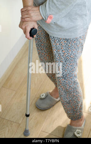 Senior woman standing avec ses mains sur les poignées d'une canne. Les soins de réadaptation et de concept. La verticale. Banque D'Images