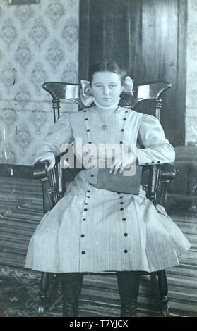 Fille dans un fauteuil à bascule victorien, 1910. L'État de New York. Le CPPR Banque D'Images