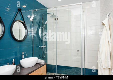 Salle de bains moderne avec un plateau intérieur en bois, deux éviers debout sur elle et miroirs ronds. Cabine de douche en verre transparent, scandinave minimaliste Banque D'Images