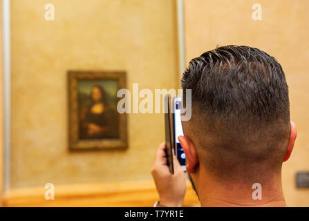 Les visiteurs du Musée du Louvre à prendre des photos de Leonardo da Vinci's Mona Lisa peinture avec leurs caméras. La peinture est l'un des plus célèbre du monde Banque D'Images