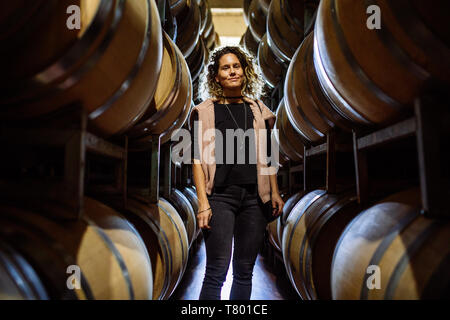 Femme de race blanche dans un milieu de barriques rangées dans Bodega Septima, Agrelo, Lujan de Cuyo, Mendoza, Argentine Banque D'Images