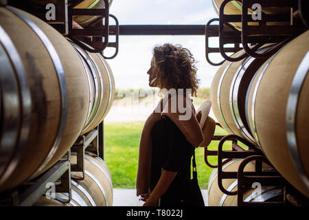 Caucasian woman profil en regardant l'éclairage entre oak barrel dans Bodega Septima, Agrelo, Lujan de Cuyo, Mendoza, Argentine Banque D'Images