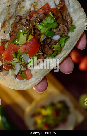 Tijuana, tacos grillés Carne asada taco holding avec des radis, limes, oignons de printemps, faible clé avec copie espace Banque D'Images