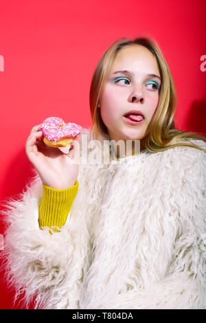 Peu cute blonde woman posing in fashion style avec donut sur fond rouge, le mode de vie de personnes concept Banque D'Images