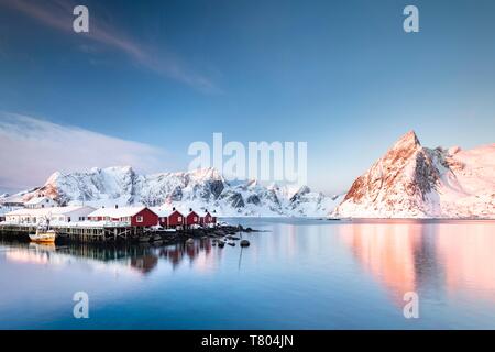 Rorbuer cabanes de Hamnoy, au lever du soleil derrière les montagnes enneigées, Olstinden, Hamnoy, Moskenesoya, Lofoten, Norvège Banque D'Images