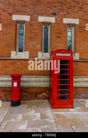 Cabine téléphonique rouge et rouge post box à côté de l'autre en face d'un bâtiment en brique. Banque D'Images