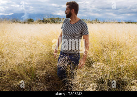 L'homme dans sa fin des années trente la mi-mi quarantaine, posant dans un champ d'herbe jaune dans Bodega Septima Winery à Mendoza, Argentine Banque D'Images