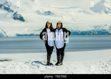 Deux américaines, les touristes à Penguin Onesies sur journée ensoleillée, posant sur les glaciers, l'Antarctique, régions polaires Banque D'Images