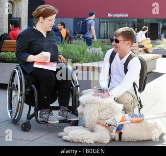 25 avril 2019, Saxe, Leipzig : l'élève aveugle Sebastian Schulze s'agenouille avec son chien-guide, le Roi Soleil, caniche à côté de l'élève handicapé Madeleine Littwin assis dans un fauteuil roulant sur le campus de l'Université de Leipzig. Sebastian, maintenant 42, a perdu la vue il y a 14 ans et étudie maintenant les études culturelles. 31 ans, Madeleine, qui a été handicapé depuis la naissance, les études de l'éducation spéciale. Autant de louanges les efforts de l'université d'Etat à l'enseignement et s'engagent pour les étudiants handicapés et n'entraînent pas d'études. Photo : Waltraud Grubitzsch/dpa-Zentralbild/dpa Banque D'Images