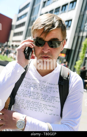 Leipzig, Allemagne. Apr 25, 2019. L'élève aveugle Sebastian Schulze est communiquant avec le campus de l'Université de Leipzig. Le poème "In meinem wilden Herzen' par Rainer Maria Rilke est brodé en braille sur son T-shirt. Sebastian, maintenant 42, a perdu la vue il y a 14 ans et étudie maintenant les études culturelles. Pendant de nombreuses années, il a été engagé pour les étudiants handicapés et n'entraînent pas d'études. Il a développé une liste de contacts avec des points de contact pour les étudiants handicapés au sein du groupe de travail. Credit : Waltraud Grubitzsch/dpa-Zentralbild/dpa/Alamy Live News Banque D'Images