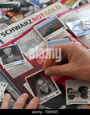 ILLUSTRATION - 10 mai 2019, Hambourg : exclusif - Une femme s'enfonce un photo de la chanteuse Helene Fischer dans la brochure 'chwarzRotGold'. Helene Fischer commerce autocollants pour un Theodor Heuss glitter photo - ou préférez-vous la chute du Mur de Berlin ? À partir de samedi, les amis de sticky photos peuvent se rassembler et échanger à travers 70 ans d'histoire de l'Allemagne. Peu avant l'anniversaire de la République fédérale d'Allemagne - la Loi fondamentale a été signé le 23 mai 1949 - le "chwarzRotGold' livret est publié. Les 333 photos montrent peu de motifs de la passé et le présent de la RFA et l'ex-RDA. (À Banque D'Images