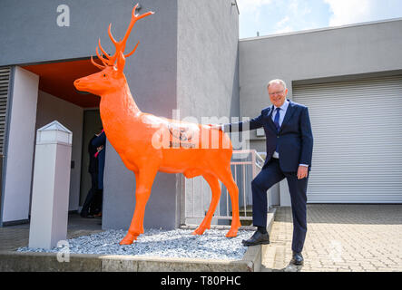 Wolfenbüttel, en Allemagne. 10 mai 2019. Stephan Weil (SPD), Ministre-président de Basse-Saxe, s'agit de l'ouverture de l'agrandissement de l'usine d'embouteillage fabricant de boissons Jägermeister et se tient à côté d'une sculpture à l'enterrement de orange Jägermeister logo. Avec cette expansion, Jägermeister a, selon ses propres informations, réalisé l'une des plus grandes usines d'embouteillage de spiritueux en Europe. Photo : Christophe Gateau/dpa dpa : Crédit photo alliance/Alamy Live News Banque D'Images