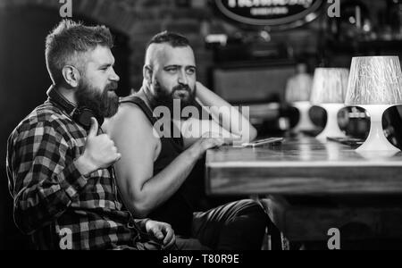 Vendredi détente dans un bar. Hipster barbu dépenser à loisir comptoir bar. Commander des boissons au bar. Les hommes avec le smartphone se reposent au bar. Dépendance Mobile concept. Téléphone mobile toujours avec moi. Banque D'Images