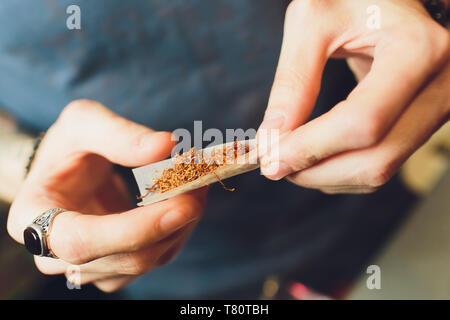 Les mains d'un homme roulant une cigarette. Le concept de la marijuana, des drogues, de la toxicomanie Banque D'Images