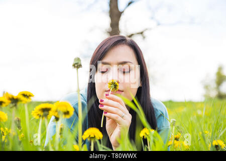 Souhaitez. Portrait de belle femme couchée dans l'herbe verte et jaune odeur pissenlit, profiter de la nature. La liberté et la nature concept. Yeux c Banque D'Images