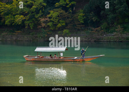 Les touristes à visiter dans un petit bateau en bois sur la rivière Oi dans l'Arashimaya Région à l'extérieur de Kyoto, Japon, Asie Banque D'Images