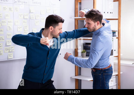 Close-up des hommes d'entrer dans une lutte femme essayant de les séparer dans Office Banque D'Images