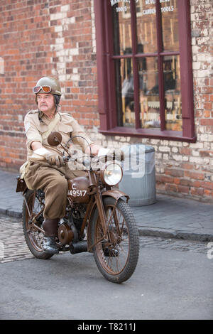 Homme senior, en uniforme militaire comme coureur militaire, isolé en plein air à cheval vintage moto, moto, Black Country Museum 1940 l'événement de la seconde Guerre mondiale. Banque D'Images