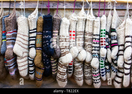 Chaussettes de laine tricotées nouvelles de différentes couleurs et ornements hanging in a row Banque D'Images