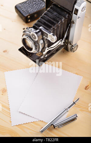 Ancienne rétro vintage appareil photo et photos anciennes avec des bords rugueux sur table en bois Banque D'Images