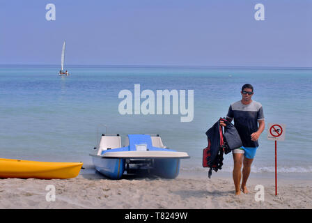 Sur une plage, dans un complexe à Varadero, Cuba, un sauveteur fixe le bateaux après utilisation par les touristes. Banque D'Images