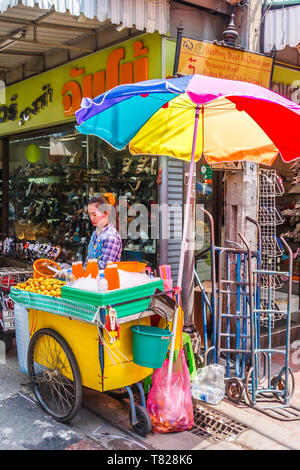 Bangkok, Thaïlande - 21 avril 2011. Vendeur de jus d'Orange sous un parapluie. Jus de fruits frais sont une drinl populaires. Banque D'Images