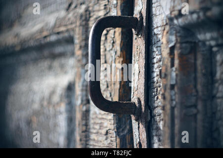 Poignée en métal rouillé sur une vieille porte en bois avec peinture en ruine, qui très probablement conduit à la maison maudite Banque D'Images