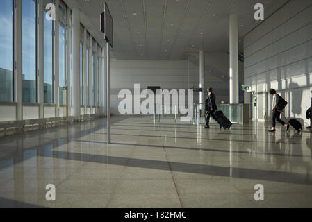 Les voyageurs d'affaires en se promenant dans les halls des départs de l'aéroport de Munich au début du matin Banque D'Images