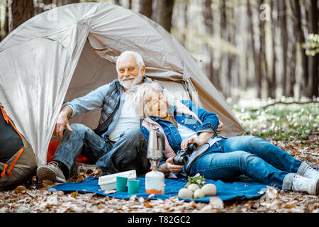 Joli couple ensemble au camping, un pique-nique sur un plaid près de la tente dans la forêt Banque D'Images