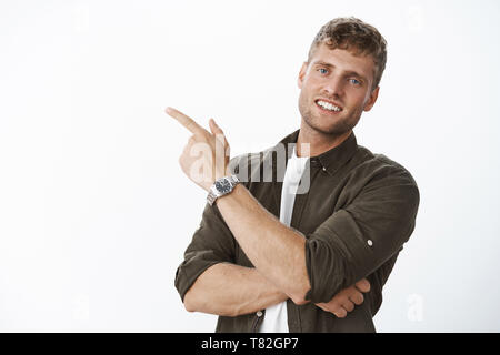 Close-up shot of friendly et beau homme européen avec les cheveux clairs et blanc sourire vers le coin en haut à gauche de l'appareil photo montrant assertif en souriant Banque D'Images