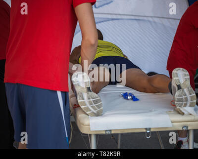 Étendu sur un lit de l'athlète tout en ayant les jambes massées après un entraînement physiques sportives. Banque D'Images