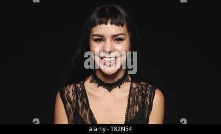 Femme souriante avec fashion piercing sur des lèvres isolé sur fond noir. Portrait of a young woman looking at camera. Banque D'Images