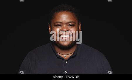 Cheerful woman isolé sur fond noir. Portrait of a smiling african man looking at camera. Banque D'Images